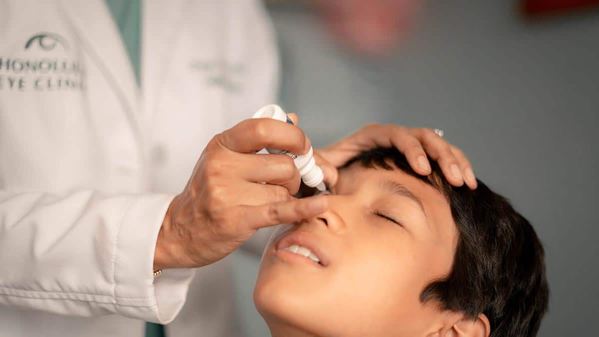 Eye doctor puts low dose atropine drop in young child to prevent nearsightedness